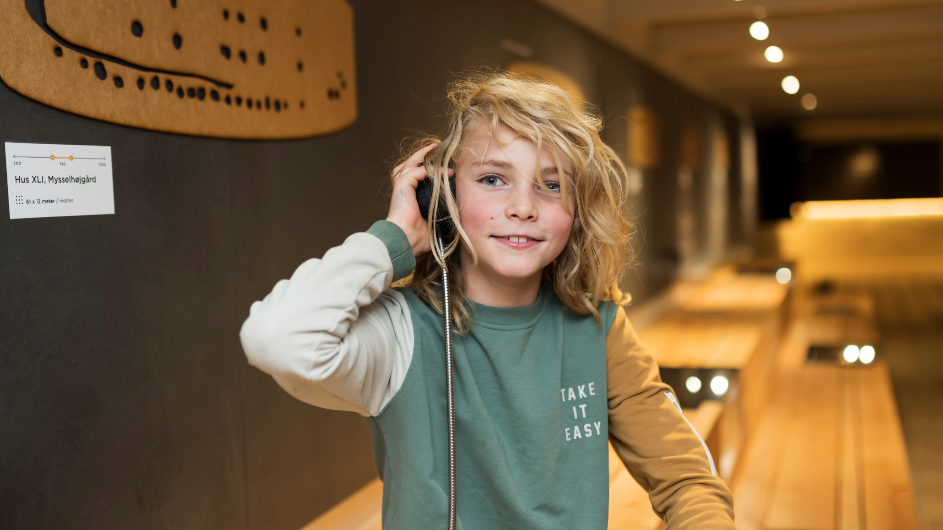 Barn lytter til lydformidling i udstillingen på Lejre Museum med arkæologiske fortællinger og historiske fund.