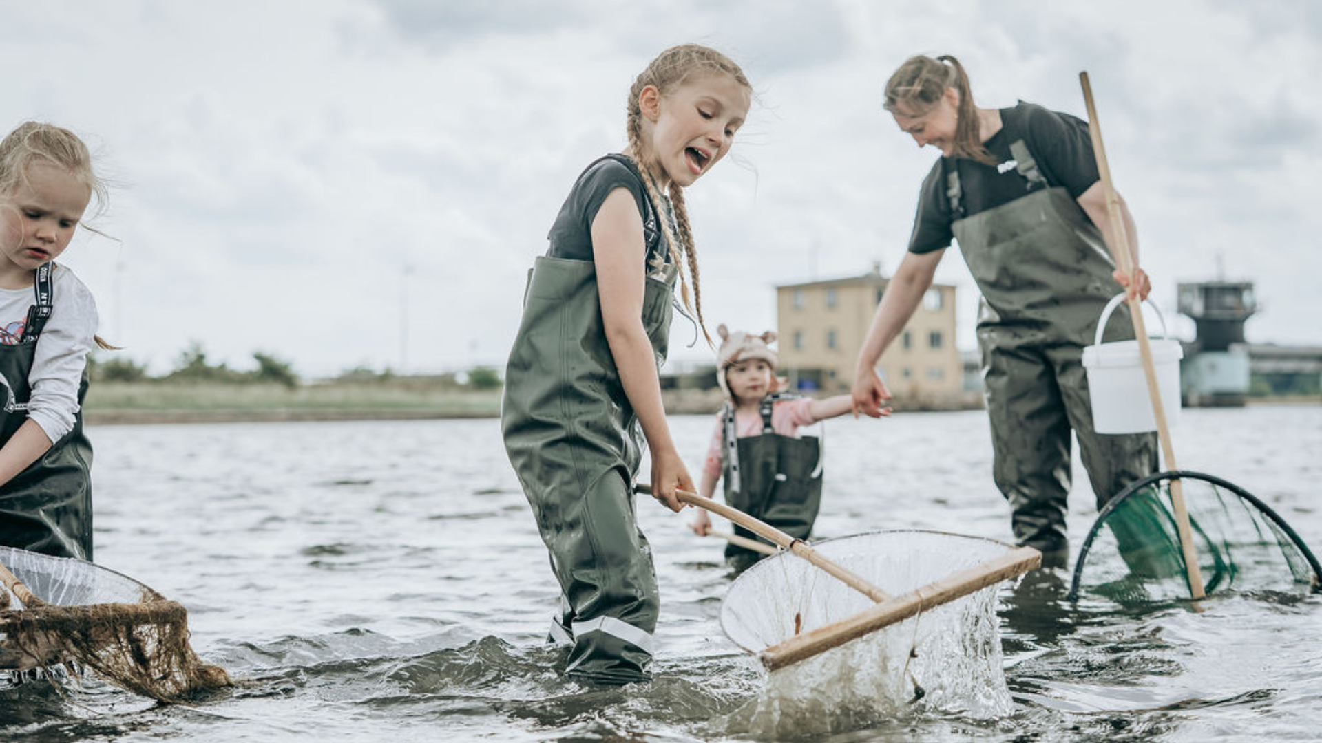 Børn og voksen udforsker livet i fjorden med fiskenet og waders ved Færgegården i Frederikssund.