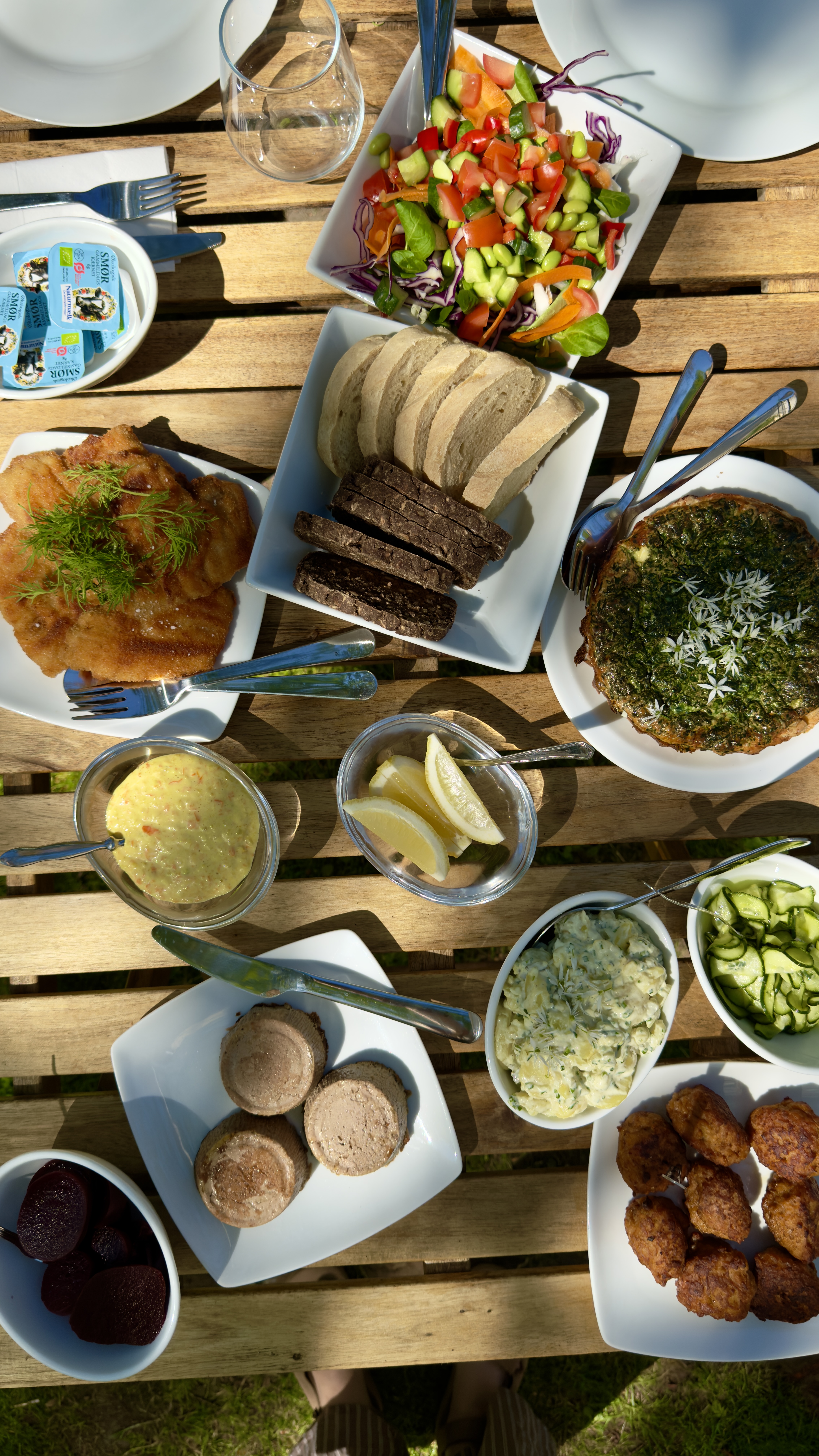 Bord dækket med hjemmelavede retter, salater, brød og tilbehør serveret udendørs hos Chefs Cottage and Garden Café.