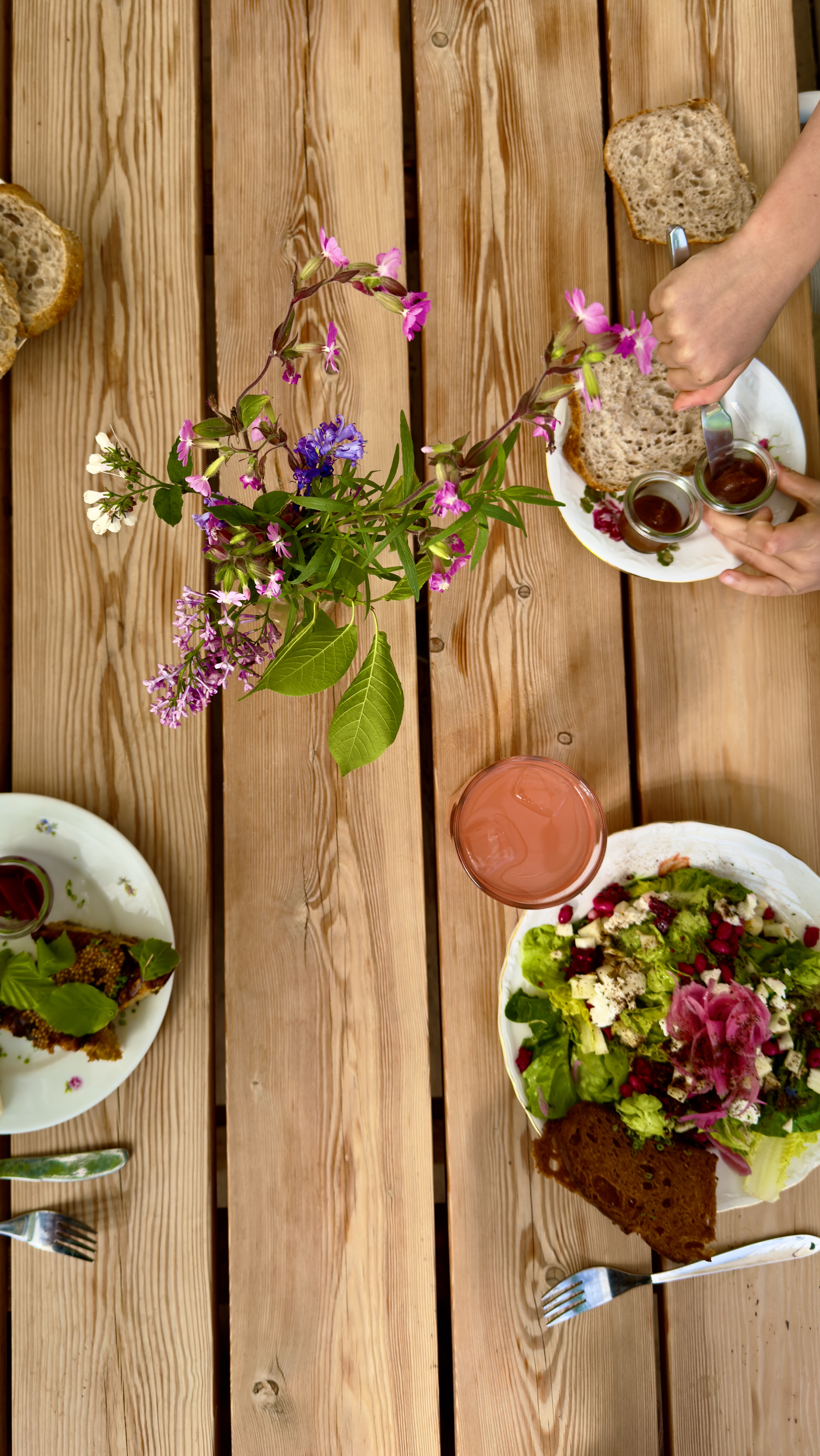 Bord dækket med økologisk salat, brød, drikkevarer og blomsterdekoration i caféen ved Sct. Hans Have.