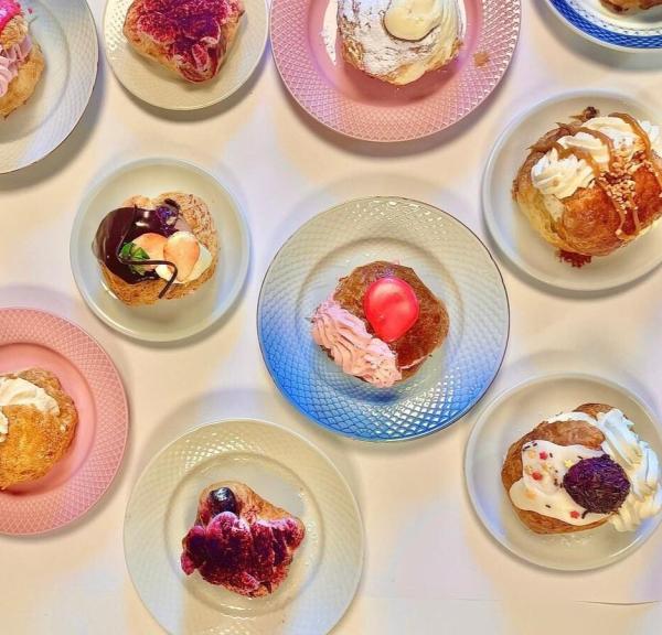 Flere farverige fastelavnsboller arrangeret på forskellige tallerkener set ovenfra.